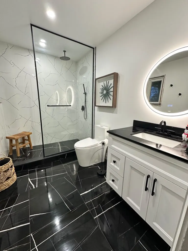 Bathroom with black marble floor, white vanity and LED mirror