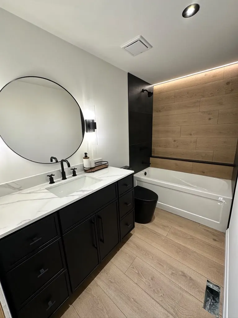 Black vanity with marble top and wood accent wall