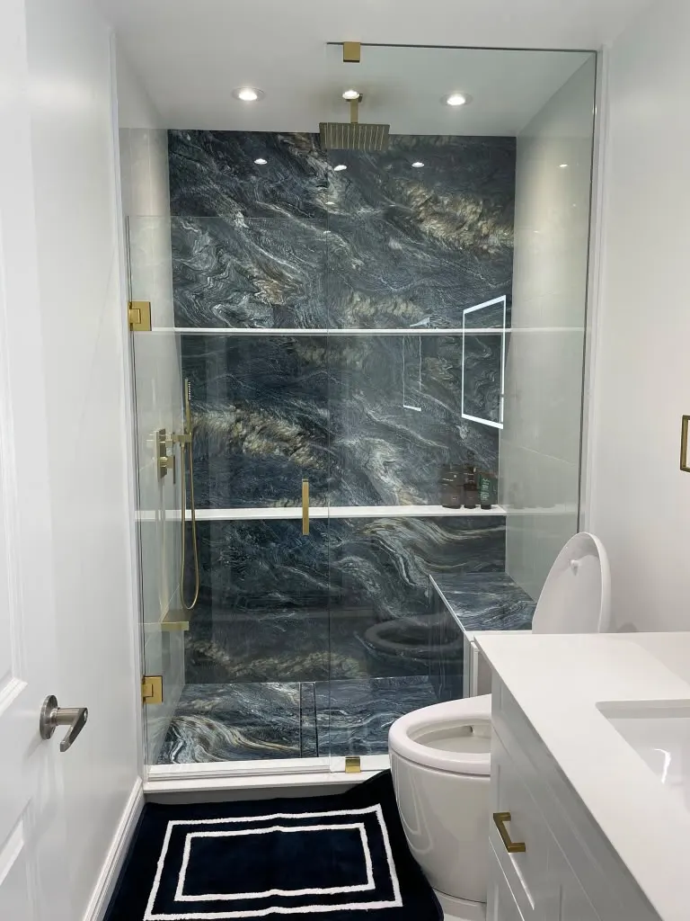 Shower with blue marble feature wall, gold fixtures and LED mirror