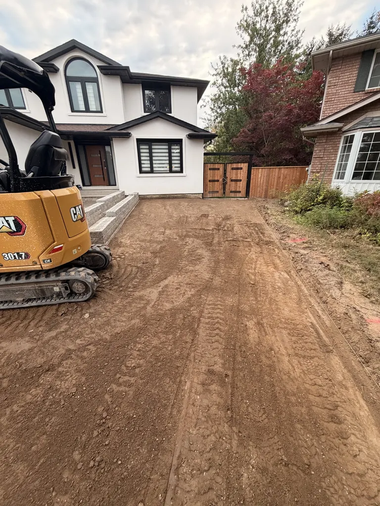 Excavator beside a freshly graded driveway area