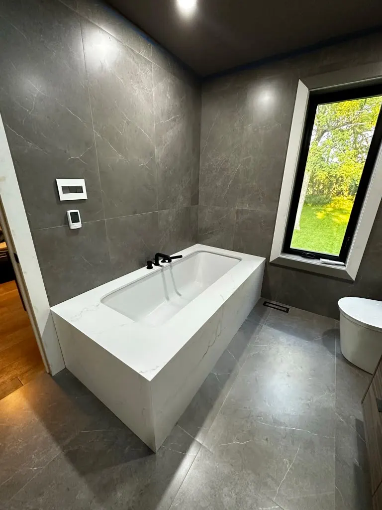 Dark tile bathroom with soaker tub and walnut vanity