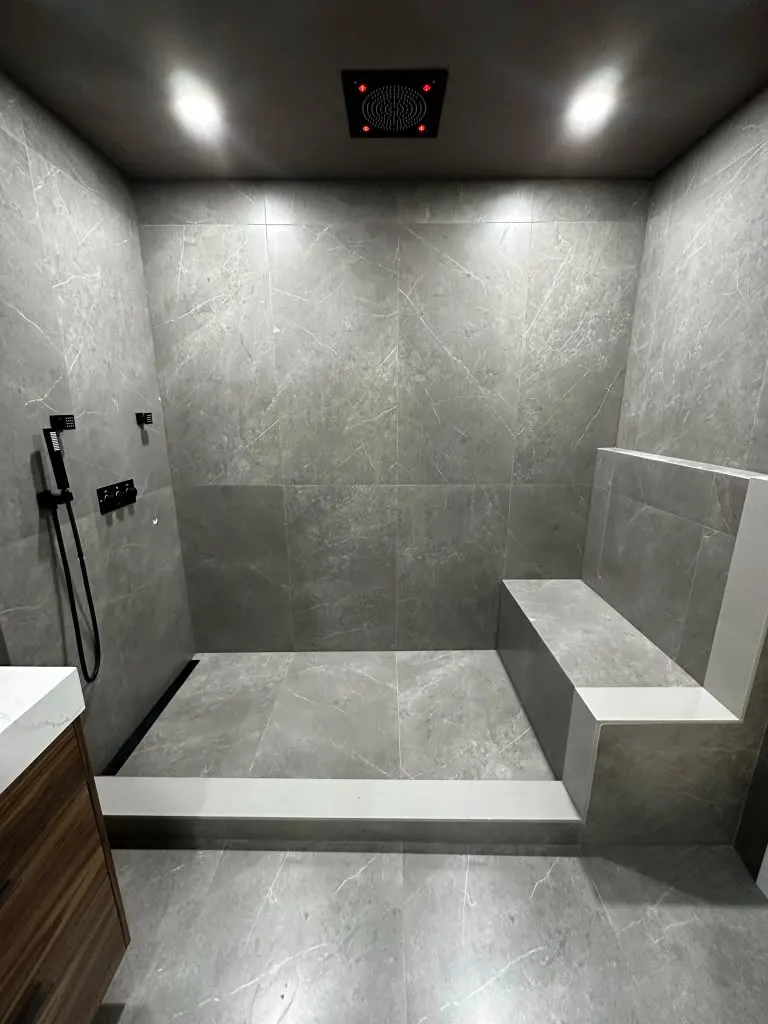 Dark large-format tile shower with built-in bench and black fixtures