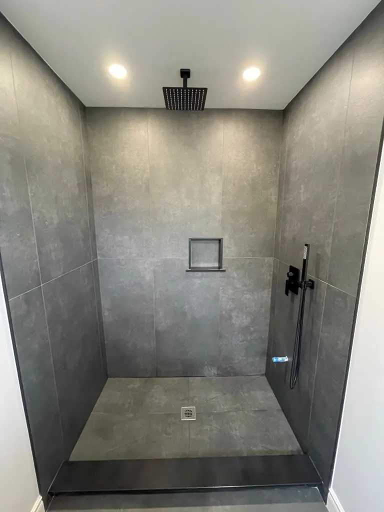 Dark tile walk-in shower with rain head and black fixtures