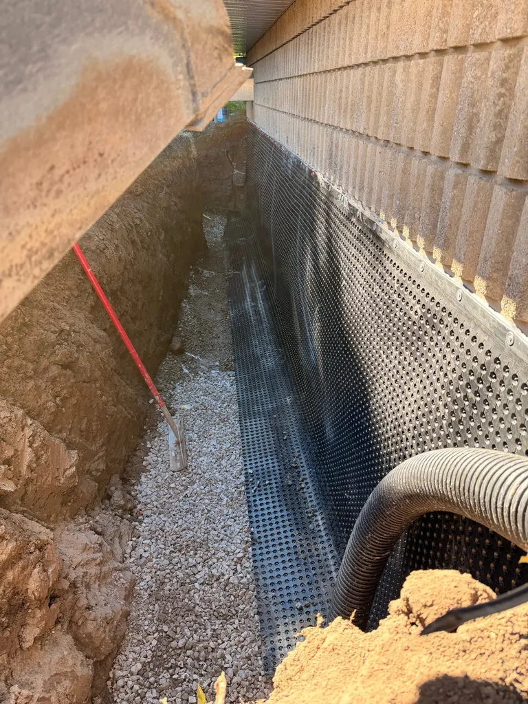 Excavated foundation trench with gravel drainage bed and dimple board