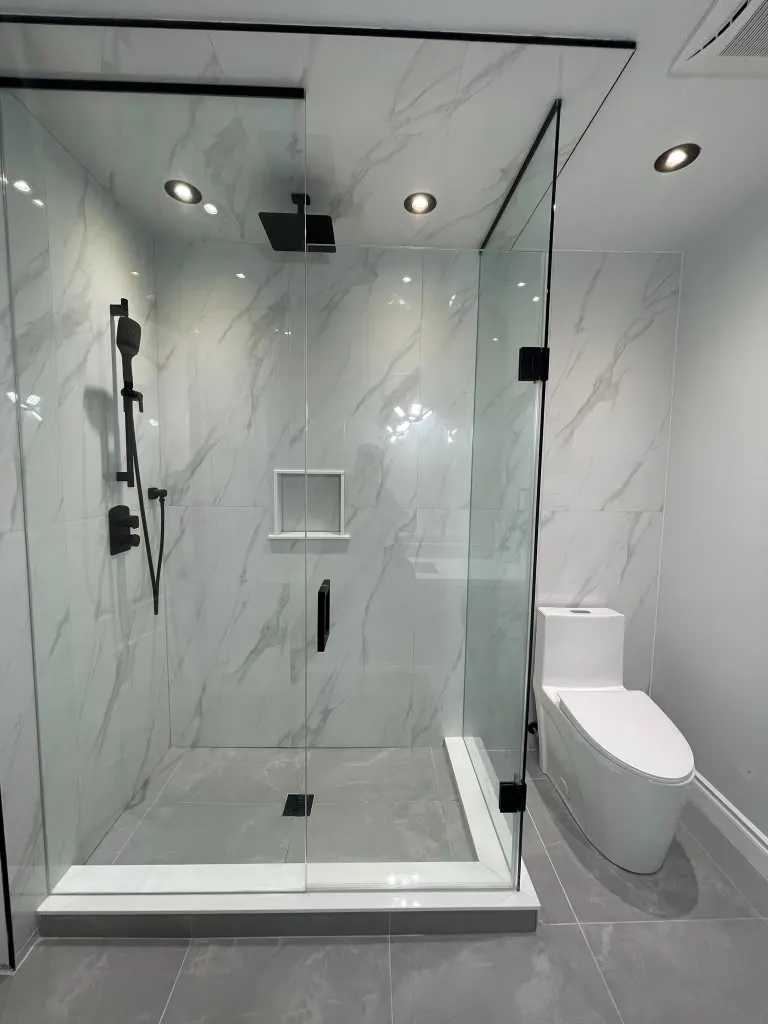 Frameless corner shower with marble-look tile and black fixtures