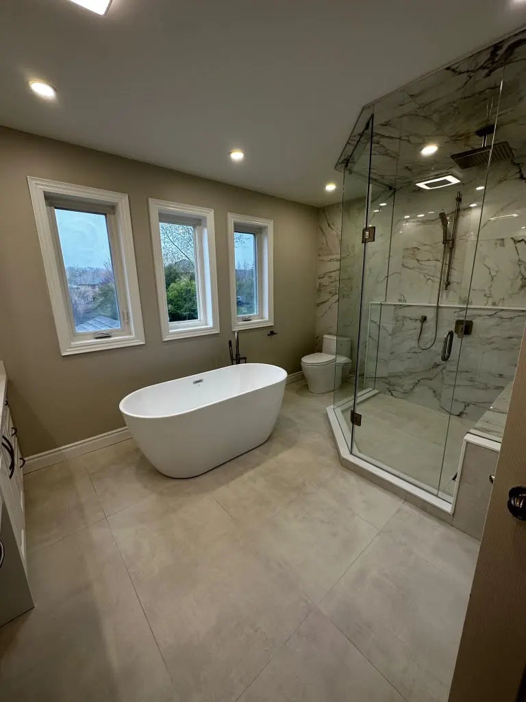 Freestanding tub beside a frameless glass corner shower